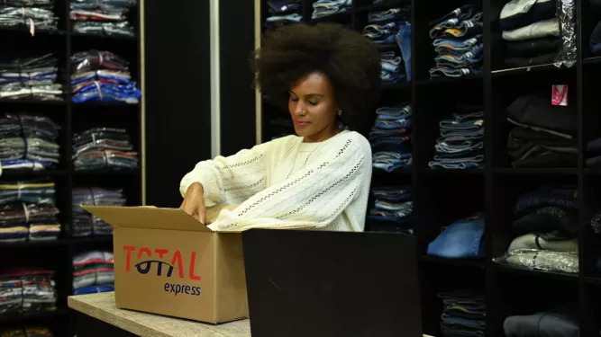 mulher negra em loja de roupa embalando produtos para enviar com a Total Express na black friday