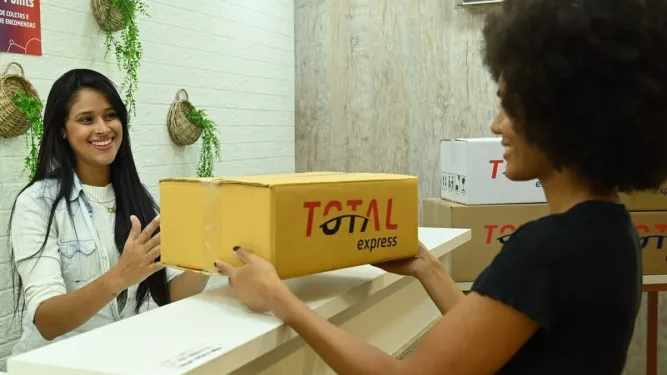 PUDO: Uma atendente entregando a encomenda para uma cliente.