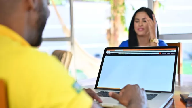 Pessoas sentadas em uma mesa realizando comprar pelo e-commerce.