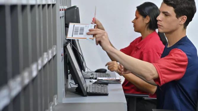 Duas pessoas atendendo o público e realizando entrega de cartões.