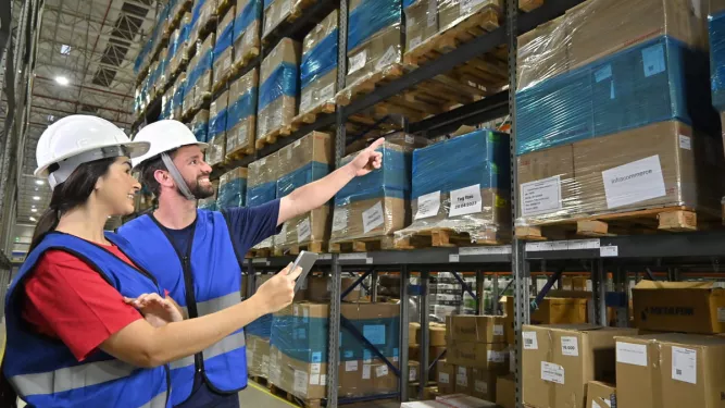 Na imagem, vemos duas pessoas com EPIs conversando sobre o processo de armazenagem.