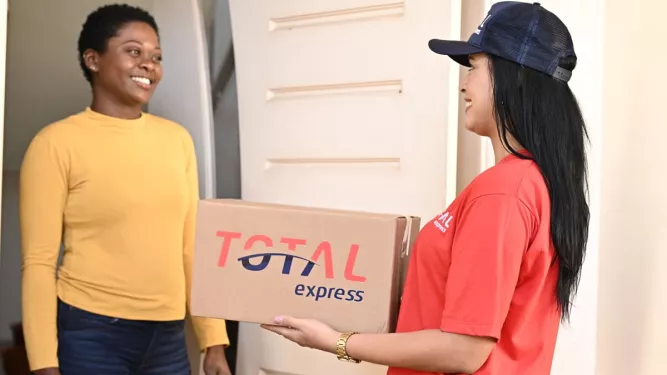 Entregadora da Total Express realizando a entrega de um pacote a uma cliente em sua residência.