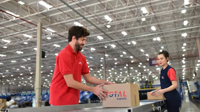 Imagem de profissionais no centro de distribuição realizando a movimentação de caixas durante o processo de "middle mile" da logística.