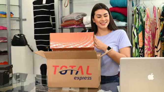 Empreendedora organizando encomenda em loja, exemplificando o processamento logístico no e-commerce.