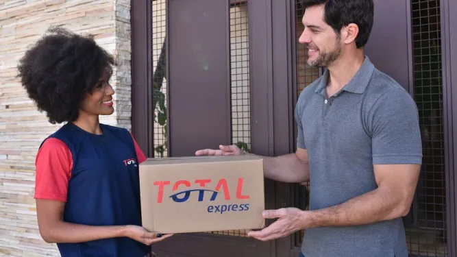 A imagem mostra uma entrega de pacote feita por um colaborador da Total Express, um exemplo de como o modelo de dropshipping funciona.