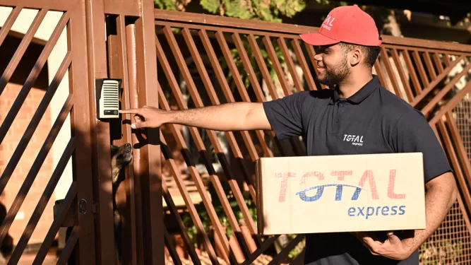 Entregador da Total Express realizando a entrega de um pacote na etapa final da logística, conhecida como last mile.