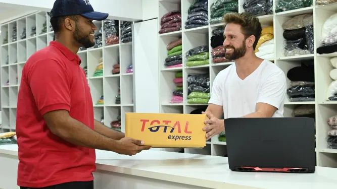 Funcionário entregando um pacote de encomenda da Total Express para um lojista em campanhas sazonais