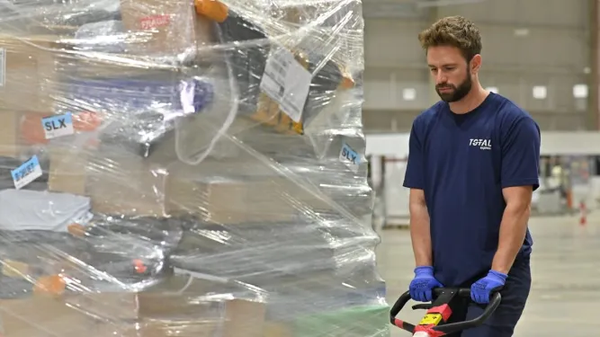 Funcionário fazendo o transporte de carga fracionada na indústria.