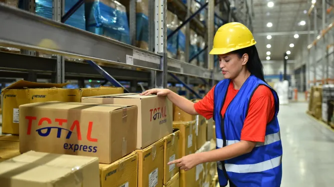 Funcionária recolhe caixas para dar inicio ao processo de logística empresarial