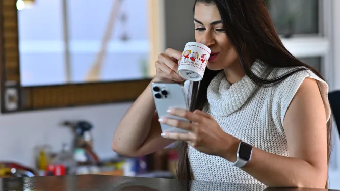 Mulher bebe café enquanto olha no celular o rastreamento de encomendas 