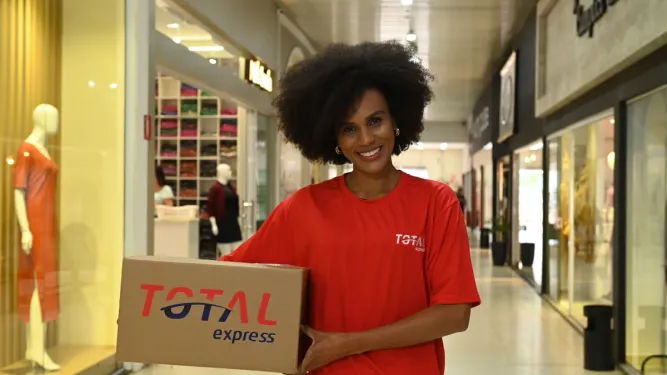 Entregadora segura uma caixa e responde se a Total Express é confiável