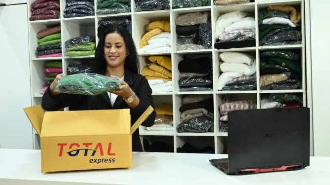 Empreendedora confere as roupas encomendadas e faz a gestão de compras do negócio