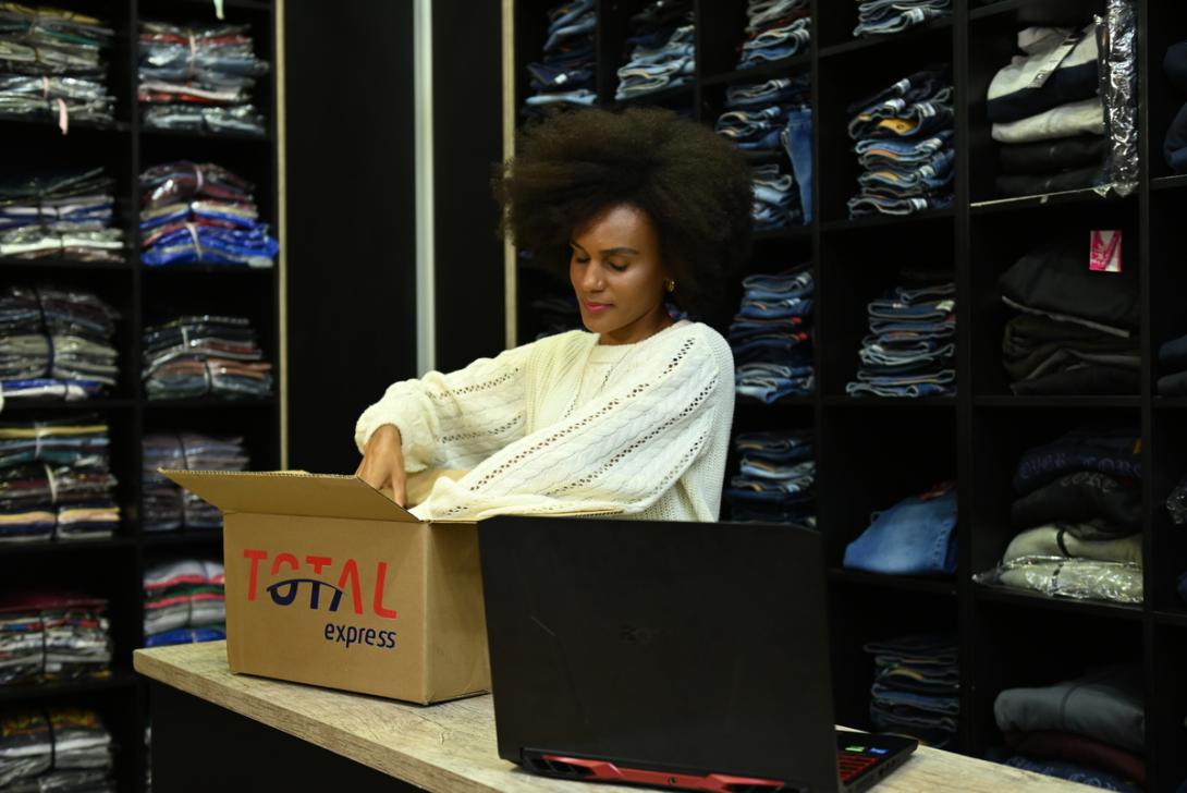 mulher negra em loja de roupa embalando produtos para enviar com a Total Express na black friday