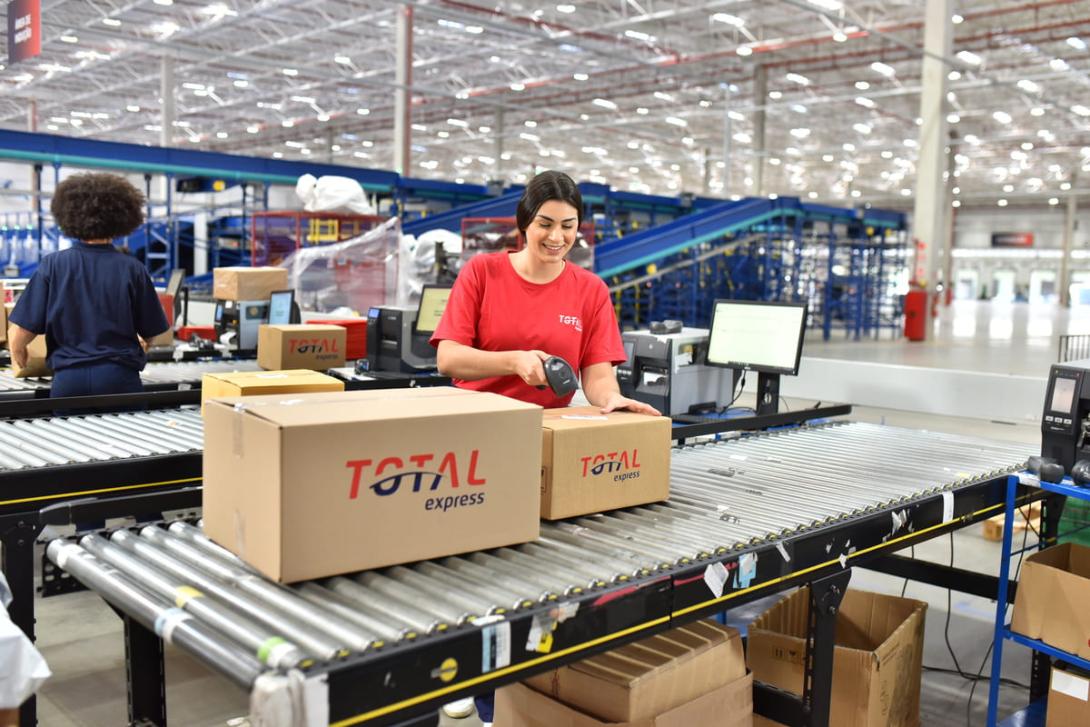 Cubagem: colaboradora aparece no centro da imagem fechando duas caixas.