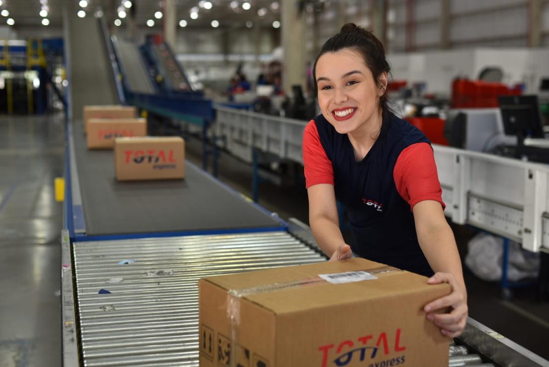 KPIs na logística: uma mulher embalando caixas com símbolo da Total Express.