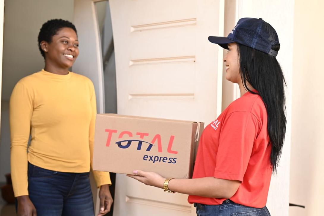 Entregadora da Total Express realizando a entrega de um pacote a uma cliente em sua residência.