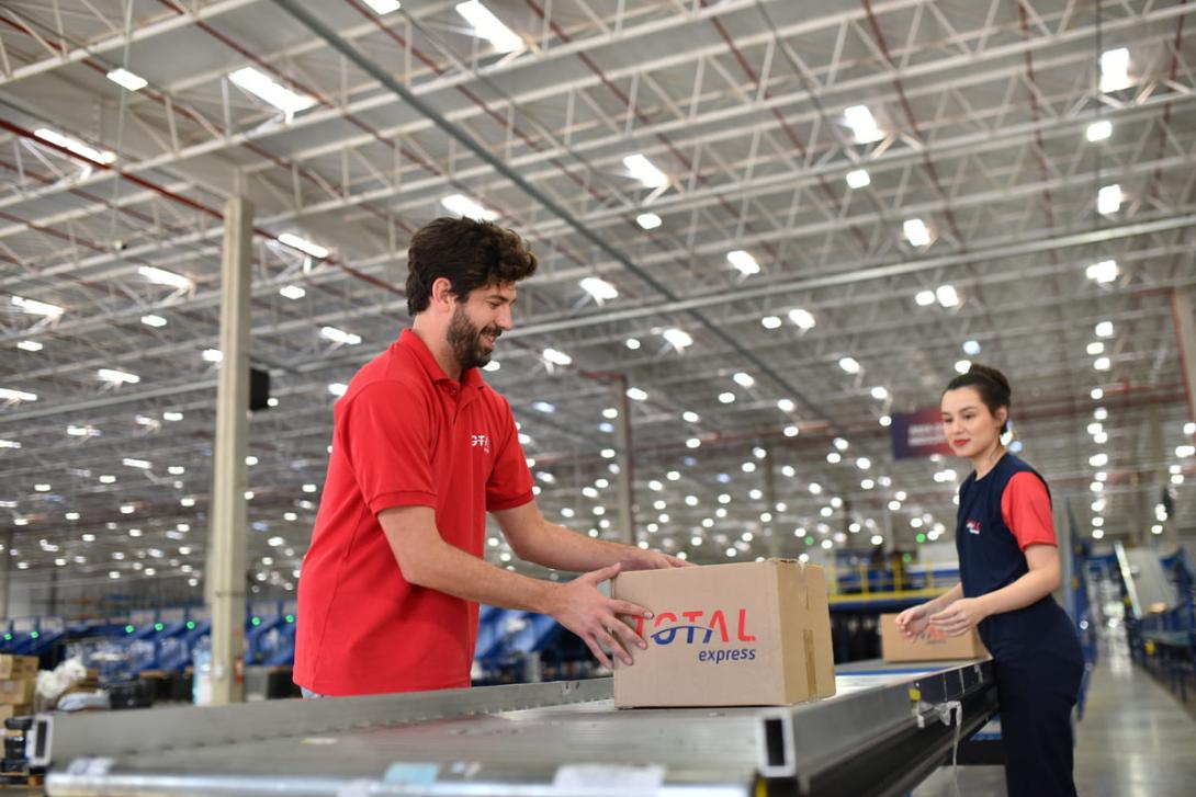 Imagem de profissionais no centro de distribuição realizando a movimentação de caixas durante o processo de "middle mile" da logística.