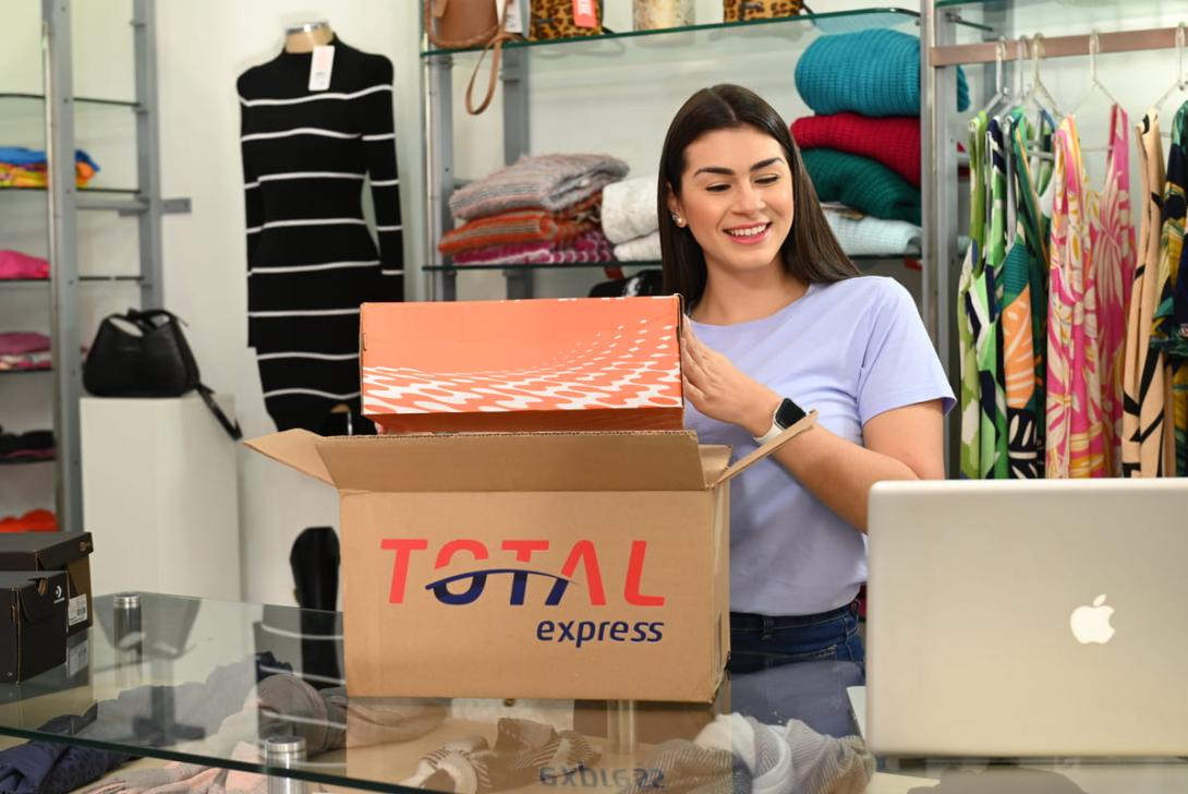 Empreendedora organizando encomenda em loja, exemplificando o processamento logístico no e-commerce.