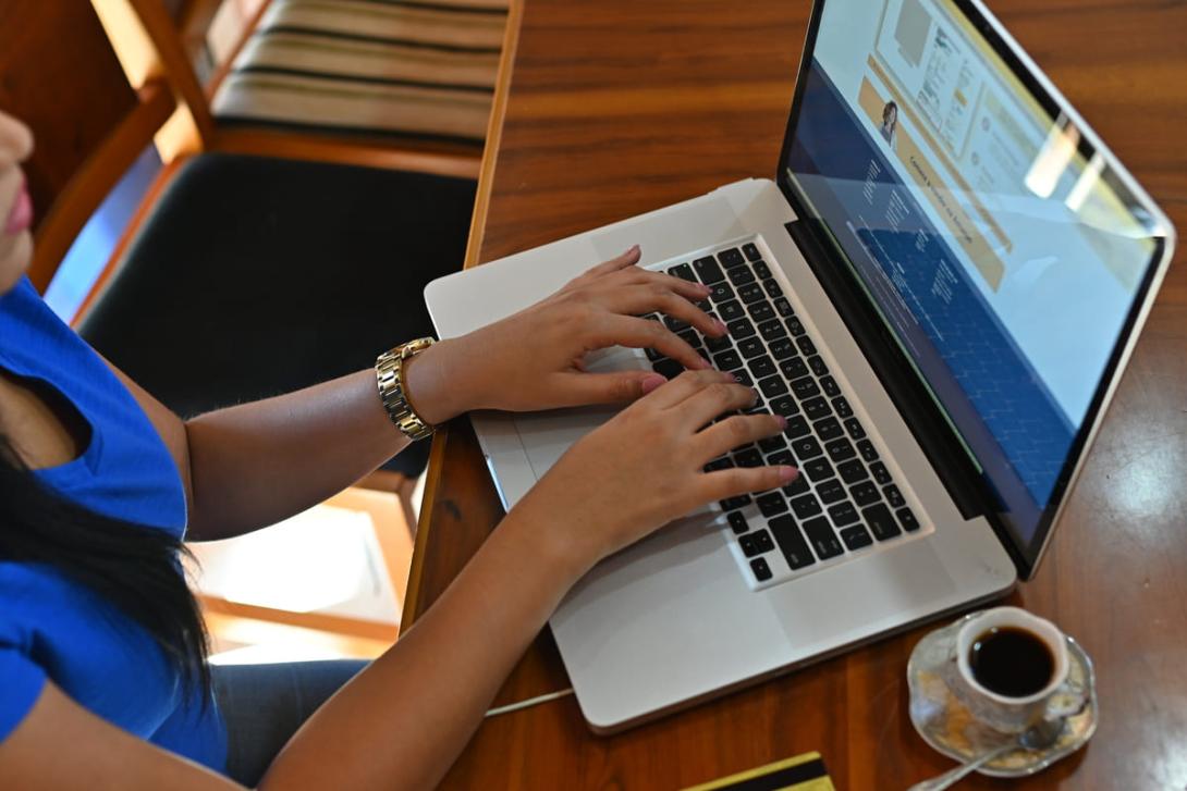 Imagem de uma pessoa digitando em um laptop, com café ao lado, acessando documentos de logística.