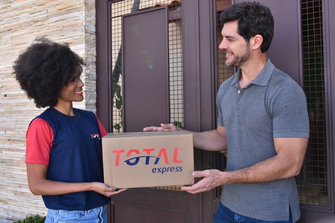 A imagem mostra uma entrega de pacote feita por um colaborador da Total Express, um exemplo de como o modelo de dropshipping funciona.
