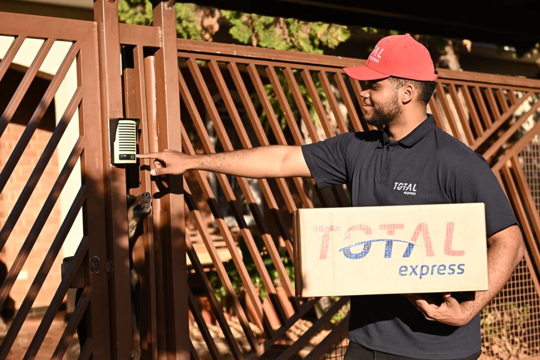 Entregador da Total Express realizando a entrega de um pacote na etapa final da logística, conhecida como last mile.