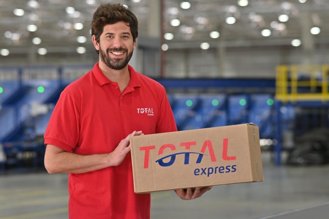 Funcionário segurando embalagem de dimensões médias da Total Express