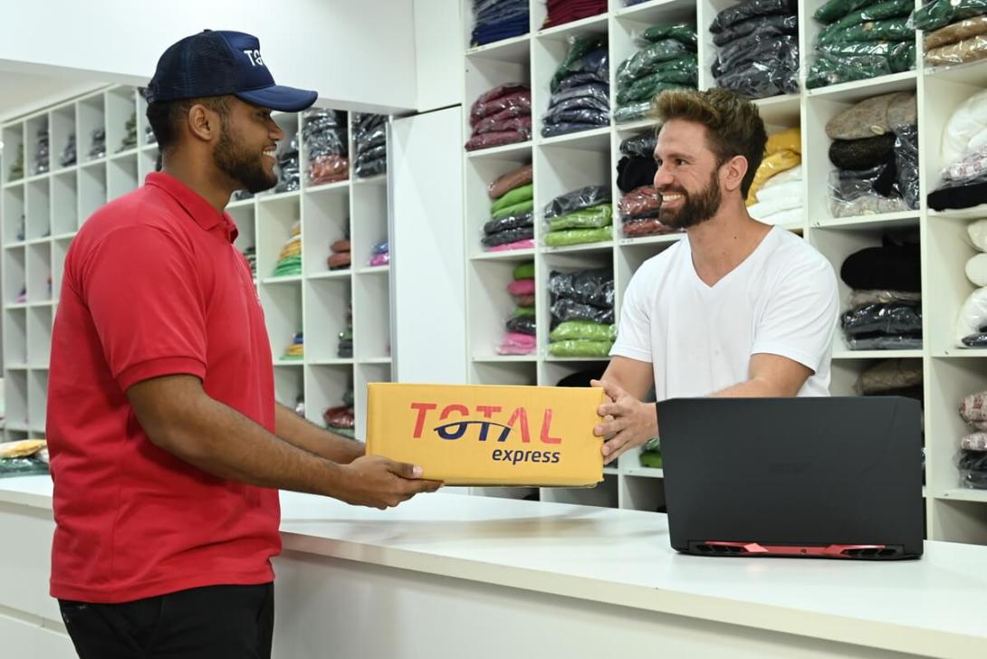 Funcionário entregando um pacote de encomenda da Total Express para um lojista em campanhas sazonais
