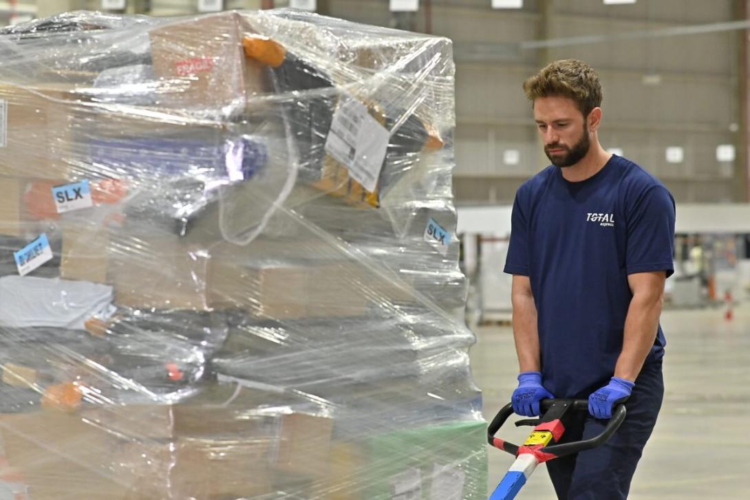 Funcionário fazendo o transporte de carga fracionada na indústria.