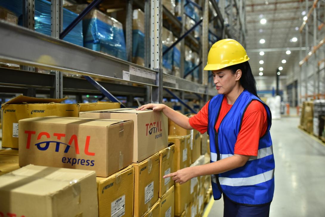 Funcionária recolhe caixas para dar inicio ao processo de logística empresarial