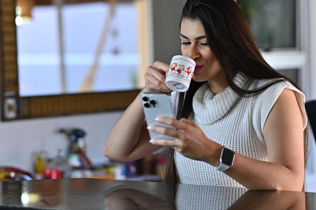 Mulher bebe café enquanto olha no celular o rastreamento de encomendas 